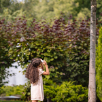 Little girl in yard inspecting trees in yard